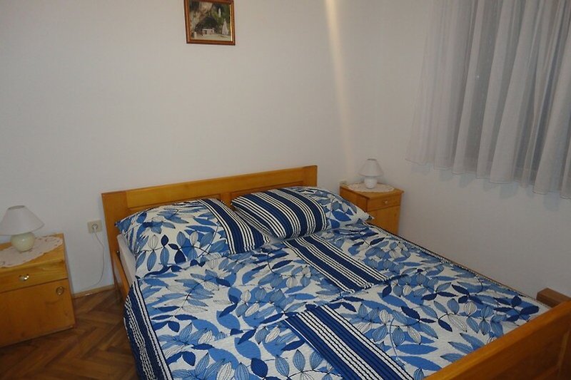 Schlafzimmer mit gemütlichem Bett und Fenster mit Vorhang.