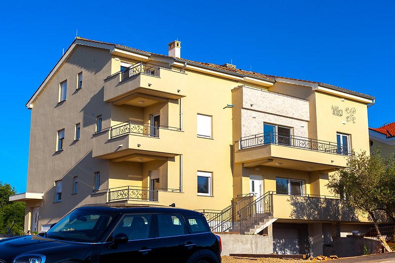 Modernes Haus mit blauer Fassade, SUV und gepflegtem Garten.