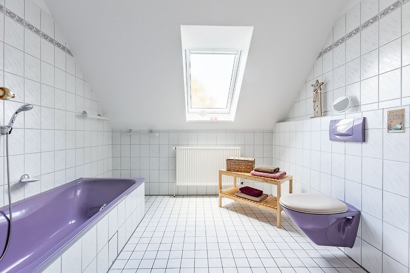 Schönes Badezimmer mit lila Fliesen, Fenster und Badewanne.