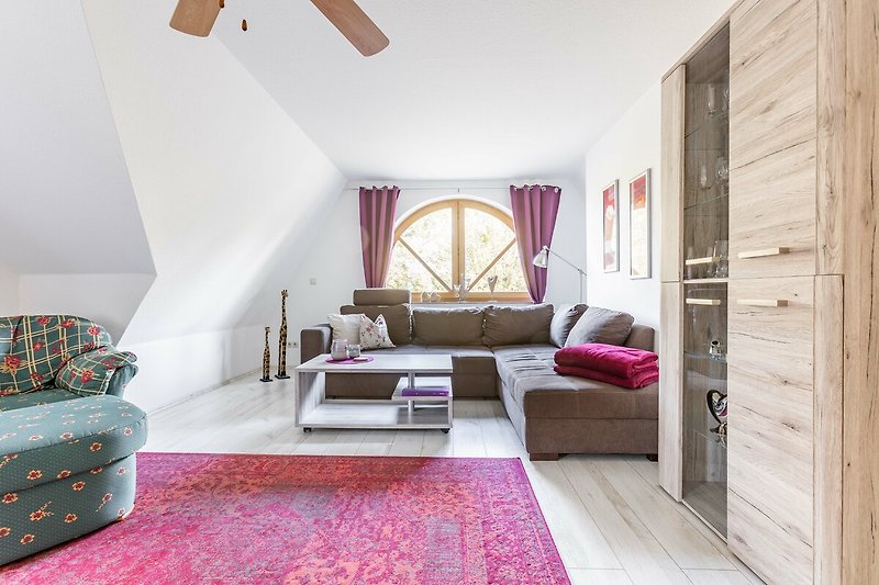 Gemütliches Wohnzimmer mit lila Akzenten, bequemer Couch und Holzmöbeln.