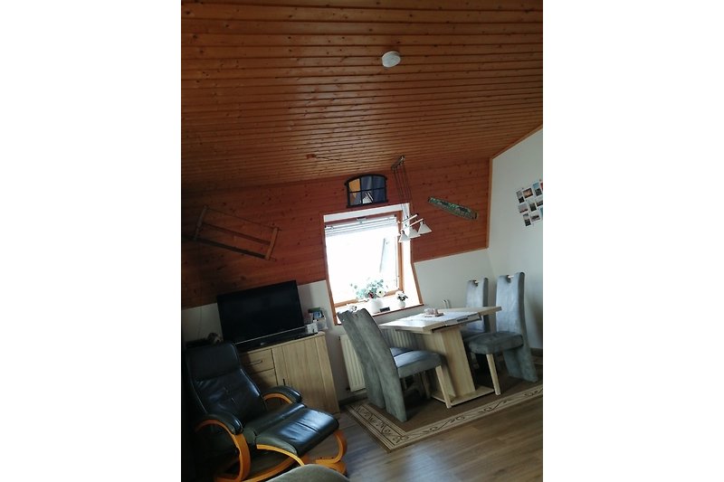 Wohnzimmer mit moderner Einrichtung, Fernseher, Schreibtisch und Fenster.