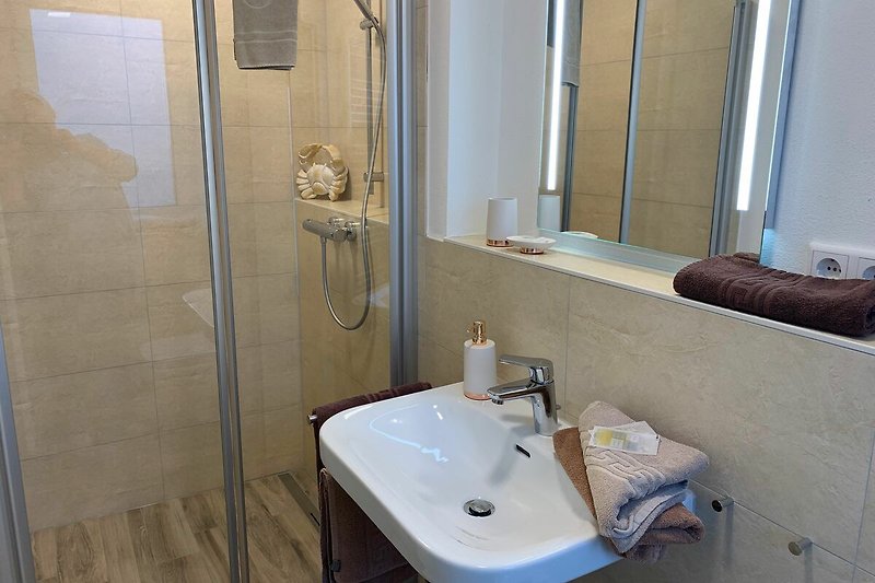 Modernes Badezimmer mit Spiegel, Waschbecken und bodentiefer Dusche.