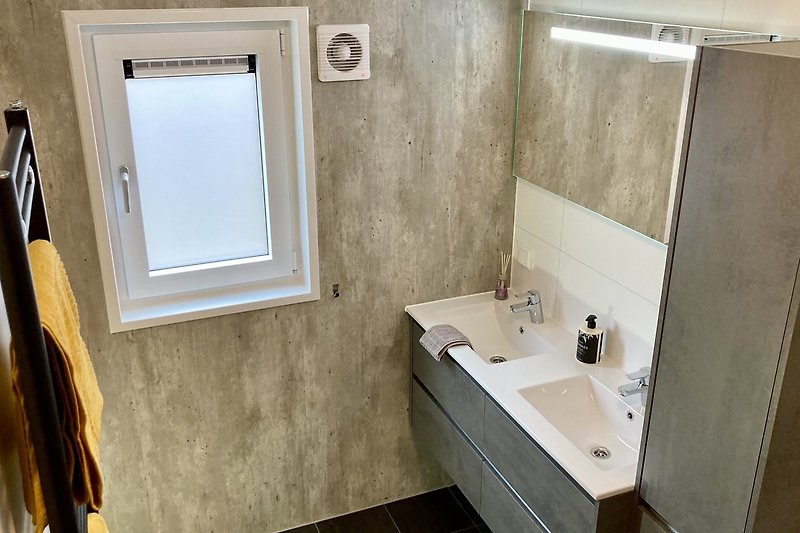 Modernes Badezimmer mit elegantem Spiegel und Keramikwaschbecken.
