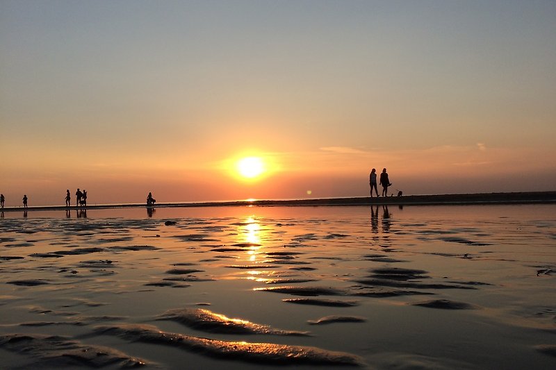 Prachtige zonsondergang aan het strand met mensen en de oceaan.
