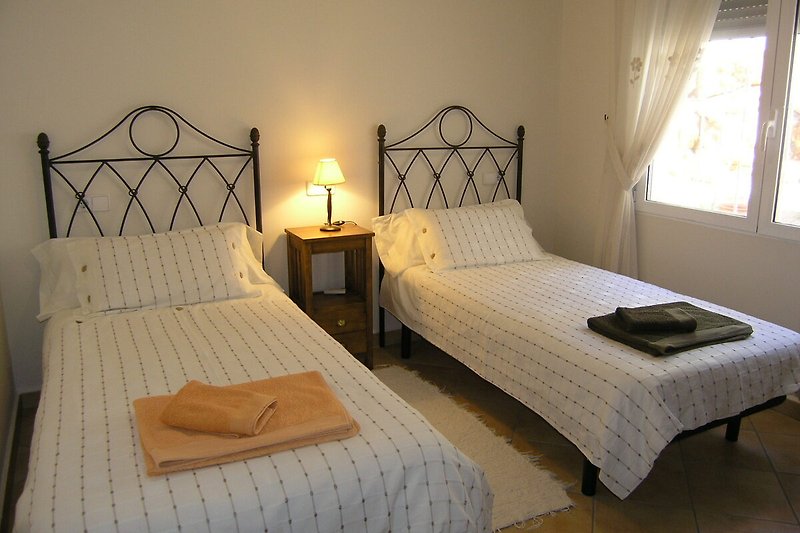 Schlafzimmer mit Holzmöbeln, Bett, Lampen und Vorhängen.