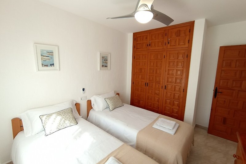 Schlafzimmer mit Holzbett, Deckenventilator und moderner Beleuchtung.