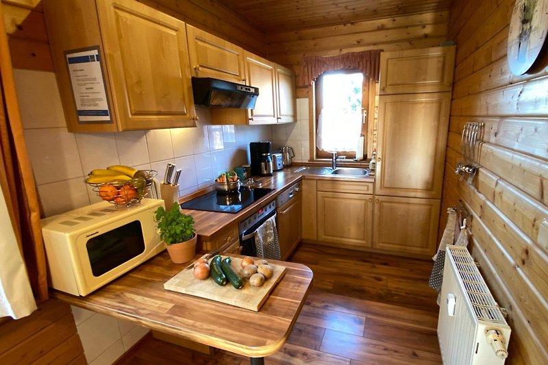 Gemütliche Küche mit Holzschränken, Arbeitsplatte und modernen Geräten.