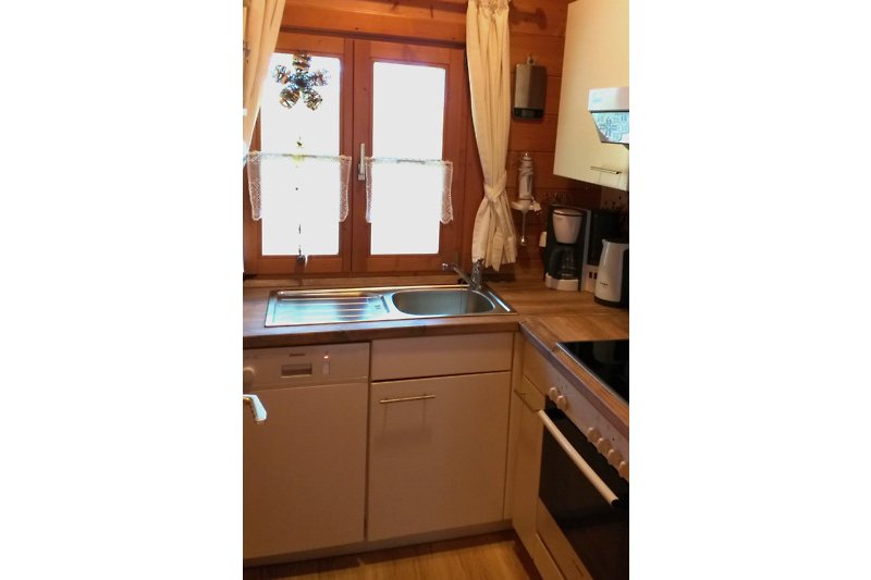 Gemütliche Küche mit stilvollen Schränken, Holzboden und Fensterdekoration.