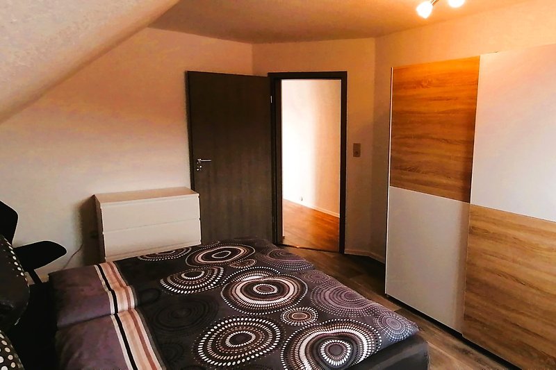 Schlafzimmer mit Boxspringbett, Bettwäsche und Fensterblick.
