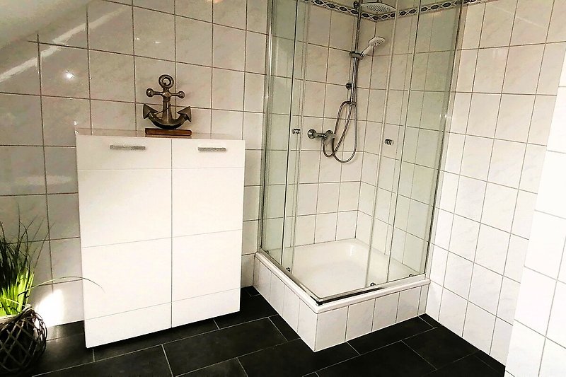 Modernes Badezimmer mit Glasdusche und Fliesen.