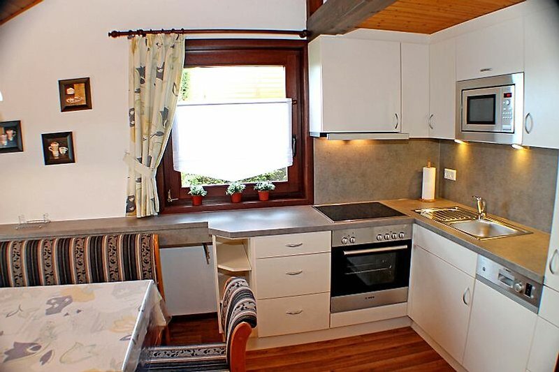 Bsp. Ferienhaus ÖFI 95 - Schöne Küche mit Holzmöbeln, Arbeitsplatte und Fenster.