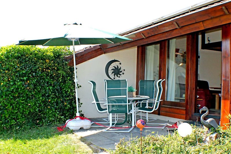 Gemütliche Terrasse mit Tisch, Stühlen und Sonnenschirm.