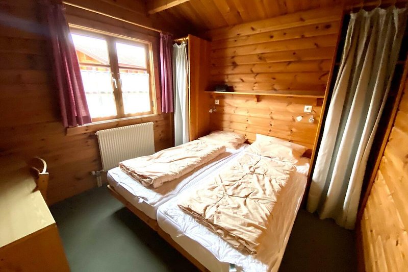Bsp. Ferienhaus LTD 46 -  Schlafzimmer mit Holzmöbeln und gemütlicher Beleuchtung.