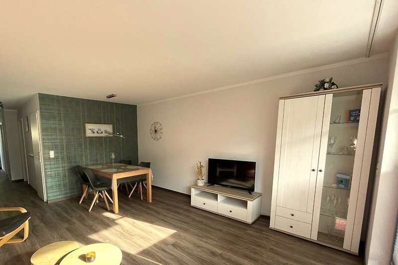 Gemütliches Wohnzimmer mit Holzmöbeln, bequemer Couch und Fernseher.