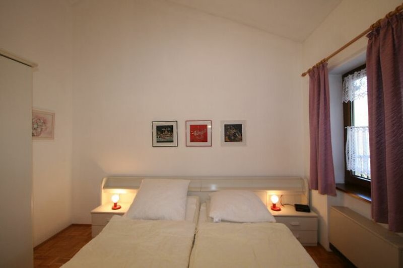 Gemütliches Schlafzimmer mit stilvollem Holzbett und Fensterdekoration.