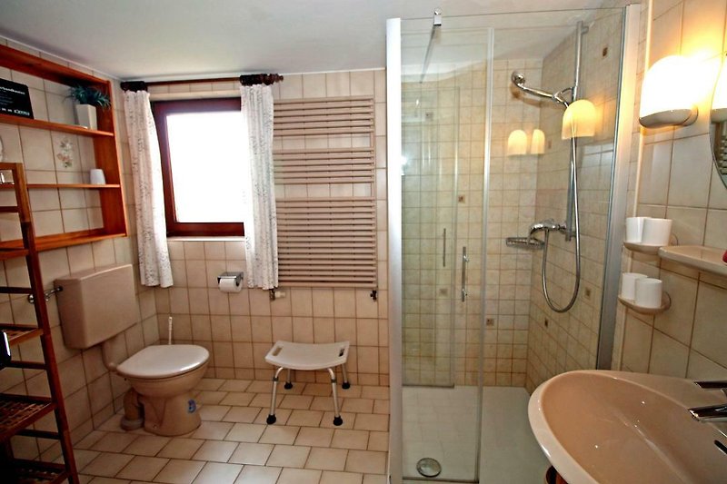 Badezimmer mit Spüle, Wasserhahn, Spiegel und Dusche.