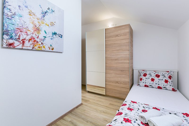 Stilvolles Schlafzimmer mit Holzboden und moderner Kunst.
