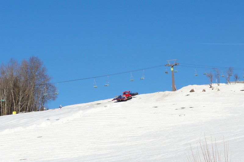 Schneebedeckter Berg mit Skihang und Seilbahn. Perfekt für Winterurlaub.