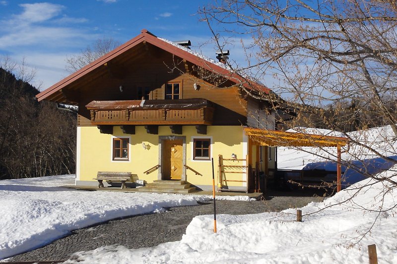 Gemütliches Holzhaus in den Bergen mit verschneiter Landschaft und Fenster. Perfekt für Winterurlaub.