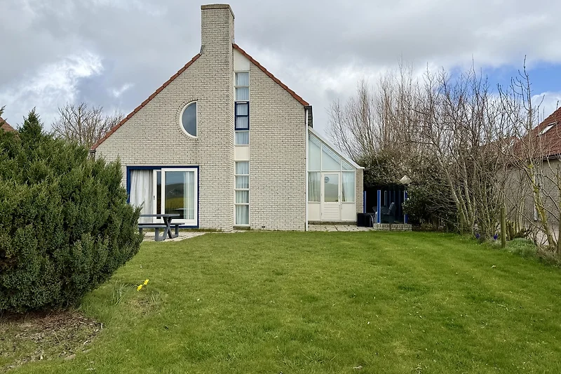 Großer Garten, gepflegter Rasen und ein schönes Haus mit Einfahrt.