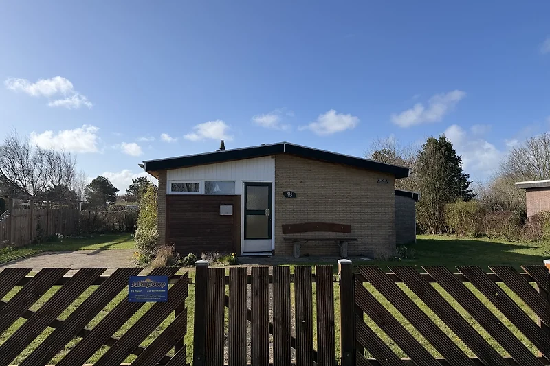 Großes Bauernhaus mit Garten, Nebengebäude und grünem Rasen.