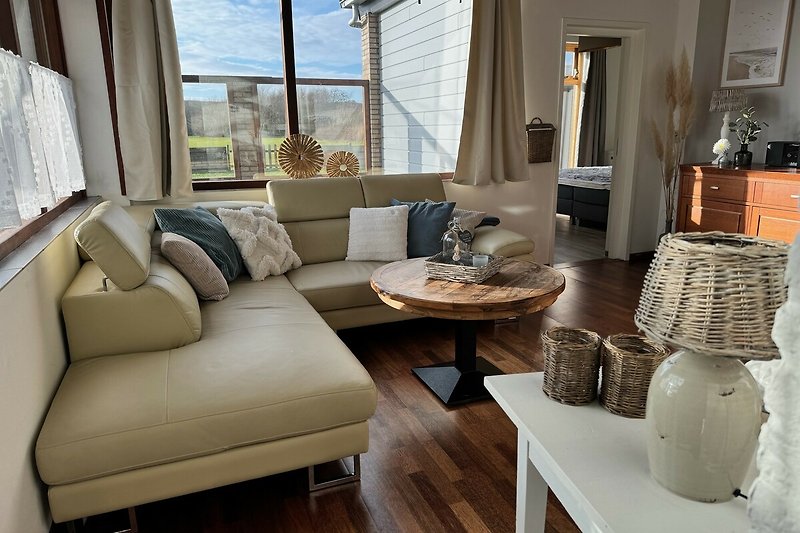 Wohnzimmer mit bequemer Couch, Tisch, Fenster und Lampe.