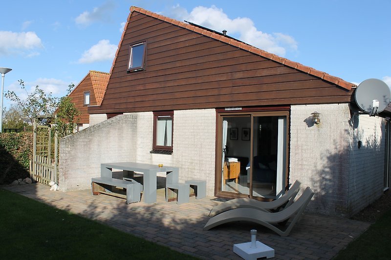 Holzhaus mit Fenstern, Pflanzen und grünem Garten.