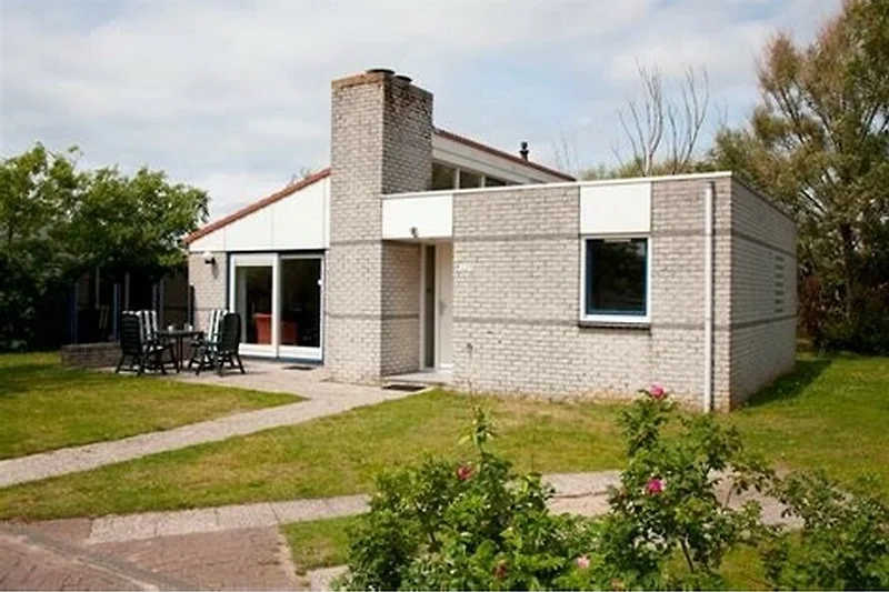 Gemütliches Haus mit Ziegelsteinfassade, Garten und Einfahrt.