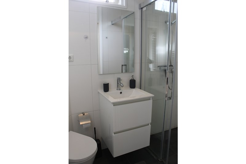 Schönes Badezimmer mit modernen Armaturen und transparenter Duschkabine.