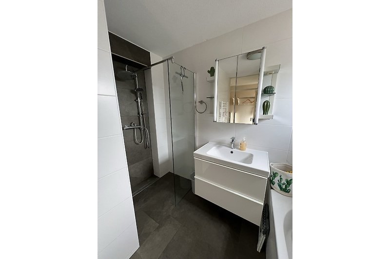 Schönes Badezimmer mit Spiegel, Waschbecken und modernen Armaturen.