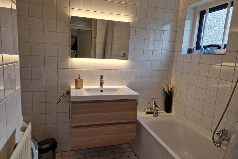 Badezimmer mit Spiegel, Waschbecken und Badewanne.