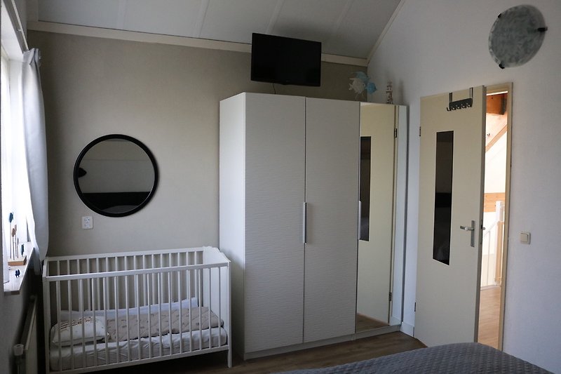 Babyzimmer mit gemütlichem Bett, Holzmöbeln und Tageslicht.