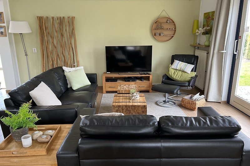 Gemütliches Wohnzimmer mit bequemer Couch, Holzmöbeln und Pflanzen.