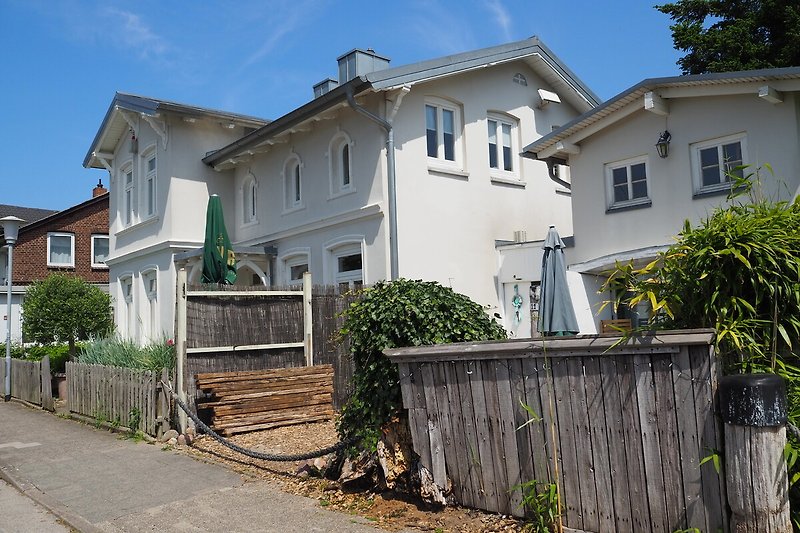 Gemütliches Haus mit Garten, Zaun und einladender Veranda.