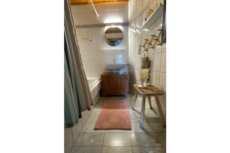 Gemütliches Badezimmer mit Holzakzenten, Spiegel und Waschbecken.