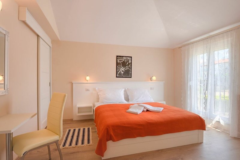 Gemütliches Schlafzimmer mit Holzmöbeln und orangefarbenen Textilien.