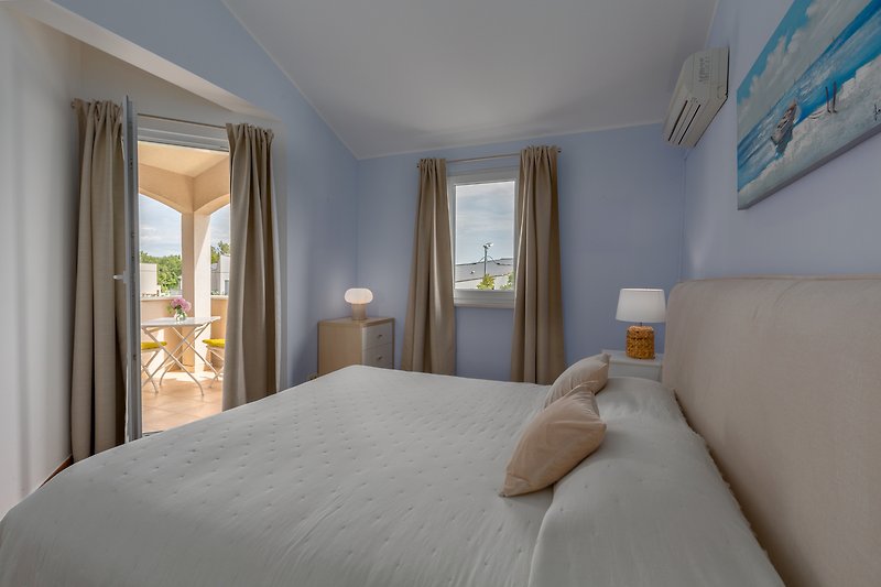 Stilvolles Schlafzimmer mit bequemem Bett, elegantem Lampenschirm und schöner Fensterdekoration.