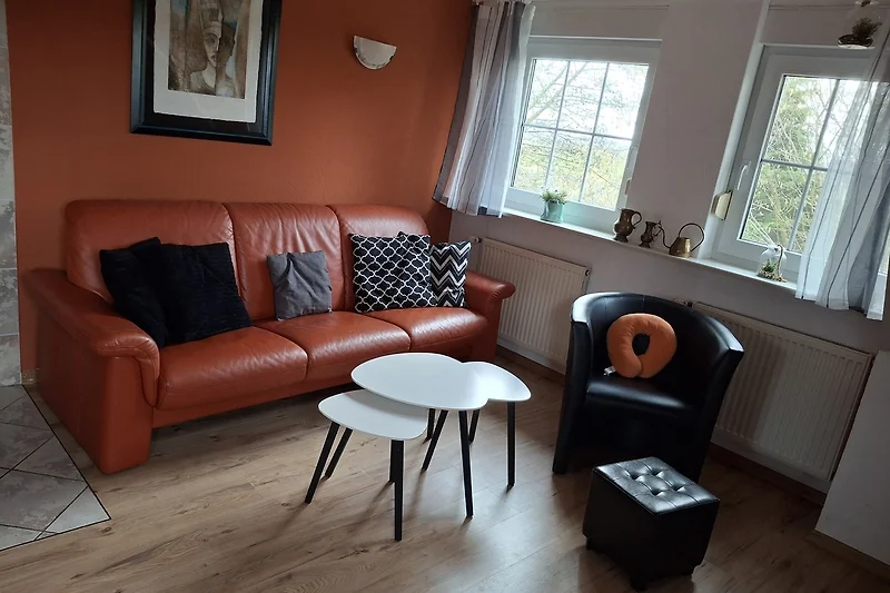 Gemütliches Wohnzimmer mit Ledersofa und Holzboden.