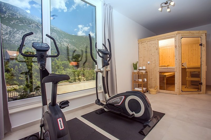 A sauna room with fitness equipment (Orbitrek and Exercise bike)