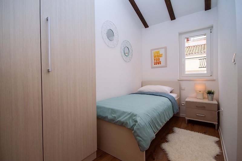 Schlafzimmer NO2 mit Doppelbett 180x200 und einem Einzelbett in einem separaten Raumteil