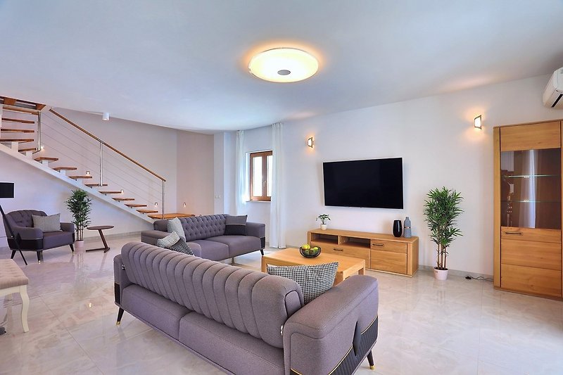 Living area with sofas and smart TV, with direct exit to the pool area and outdoor dining area