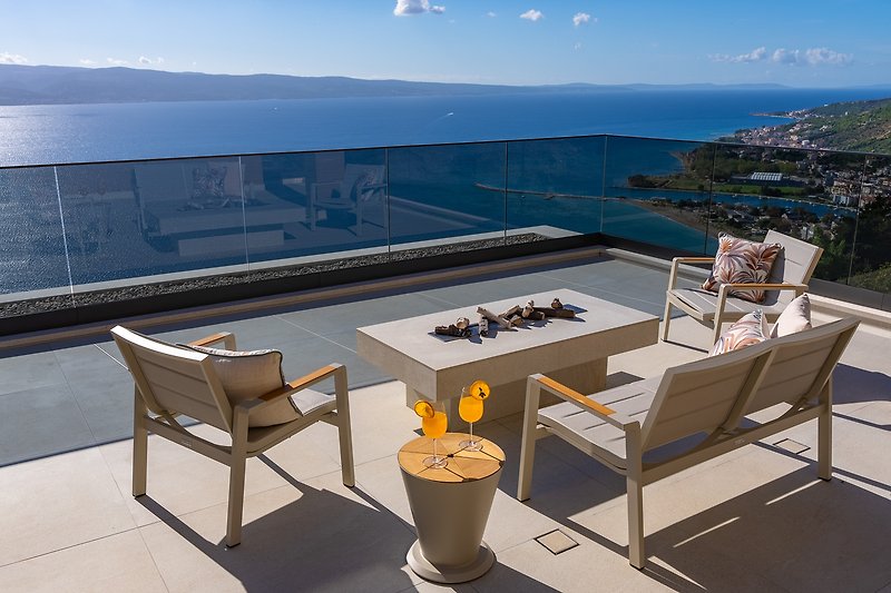 A stylish outdoor setting with comfortable furniture and a beautiful ocean view.