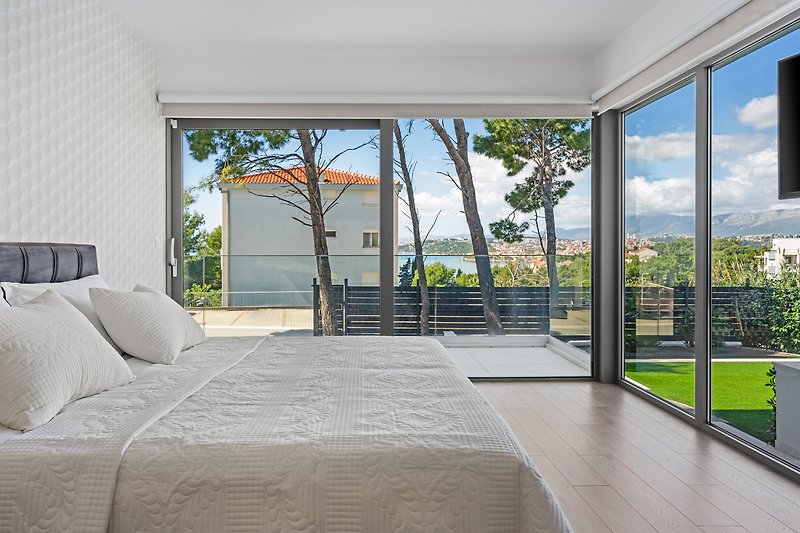 A 200x200cm king-size bed, a glass wall with blinds overlooking the neighborhood and the pool area