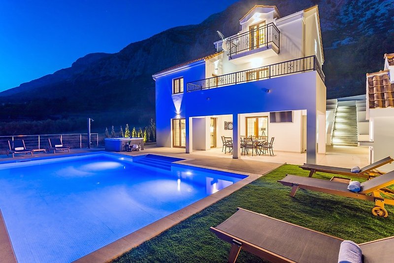 A night view on private swimming pool, Jacuzzi, covered outdoor dining area and traditional BBQ