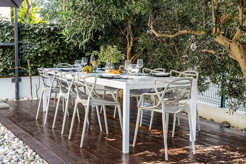 Outdoor dining area with a barbecue, surrounded with olive trees