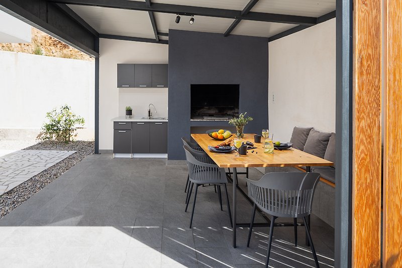 A summer kitchen with a covered dining area with a barbecue