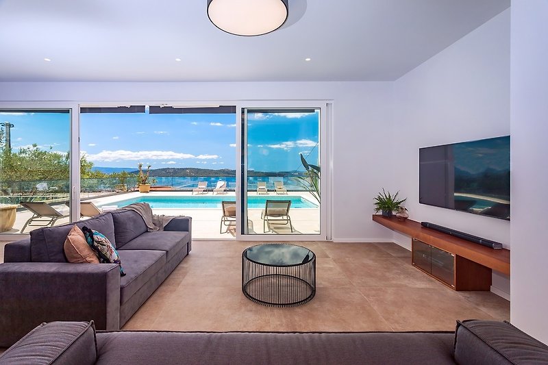 The living area has glass walls toward the pool and outdoor area.