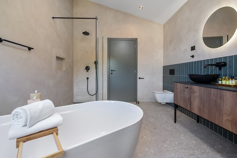 En-suite bathroom with a self-standing bathtub and a shower, a double sink, a toilet.