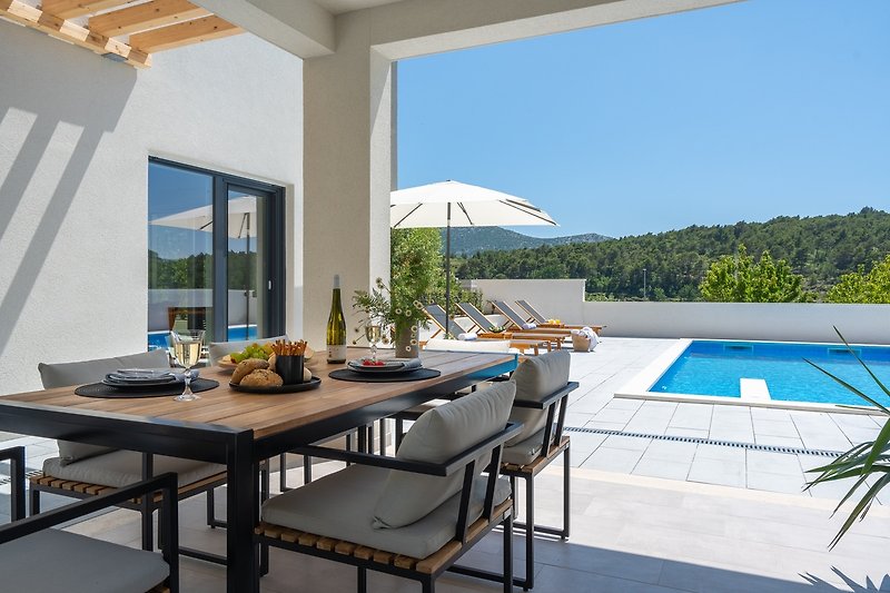 Relax by the pool with stylish outdoor furniture and a beautiful view of the azure sky.