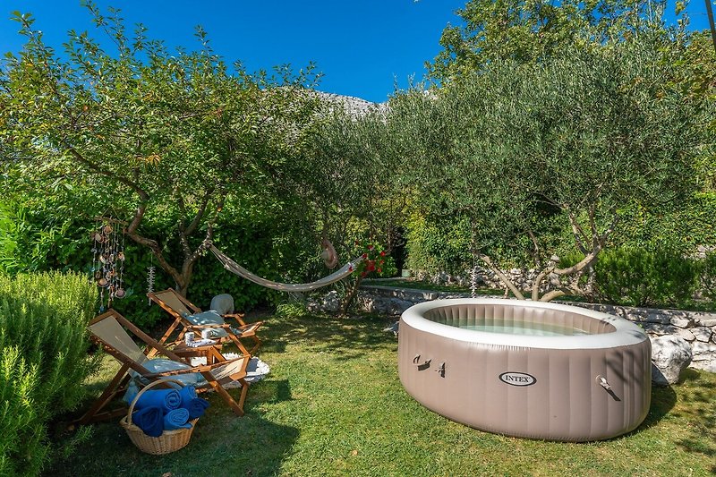 Rasenfläche mit Softub Whirpool, eine Lounge-Ecke unter den Olivenbäumen als perfekter Ort zum Schilfen und Entspannen